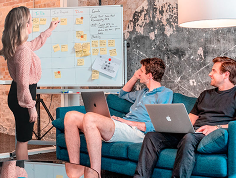 Three web designers planning a project using a whiteboard and sticky notes